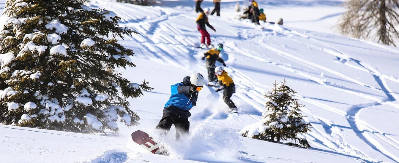 Eine Gruppe von Kindern fährt die Pisten von Madonna di Campiglio hinunter, während des Snowboard-Kurses für Kinder und Erwachsene für alle Levels mit der Scuola di Snowboard Zebra.