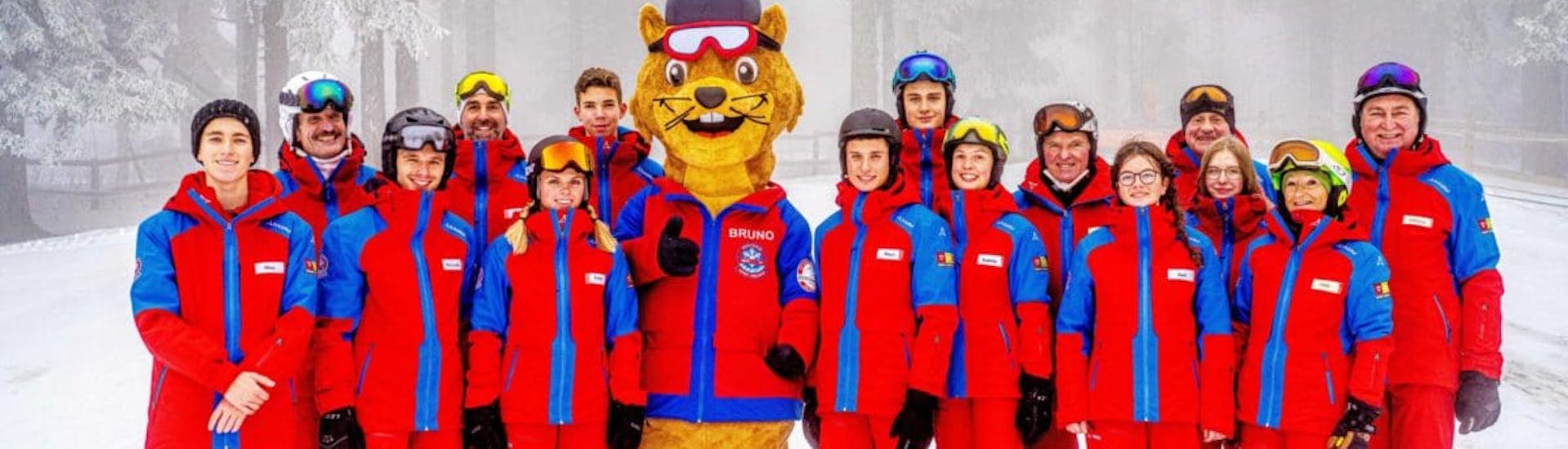Alle skileraren van skischool Sankt Englmar gaan bij de kinderskilessen (5-13 jaar) voor alle niveaus op de foto met mascotte Bruno.