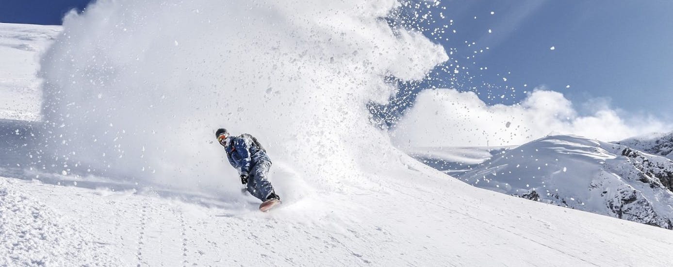 Ein Snowboarder fährt durch eine Schneewolke beim Snowboardkurs für Kinder (ab 9 J.) & Erwachsene aller Levels.