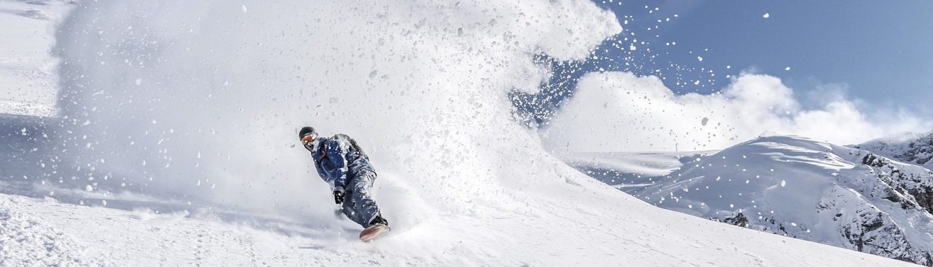 Een snowboarder rijdt door een sneeuwwolk tijdens de snowboardlessen voor kinderen (vanaf 9 jaar) & volwassenen van alle niveaus.