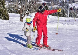 Un moniteur de ski montre la piste à un enfant pendant leur Cours de ski Enfants (3-12 ans) pour Débutants - Demi-journée avec Skischule Jochberg.