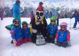 Een groep jonge skiërs gaat op de foto met de mascotte Bobi in Bobi's Snowkindergarden (2,5-4 j.) voor beginners met skischool Grächen - Zenklusen Sport.
