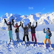 Een groep jonge skiërs geniet van het mooie weer bij de kinderskilessen (4-15 j.) voor gevorderden met Skischule Grächen - Zenklusen Sport.