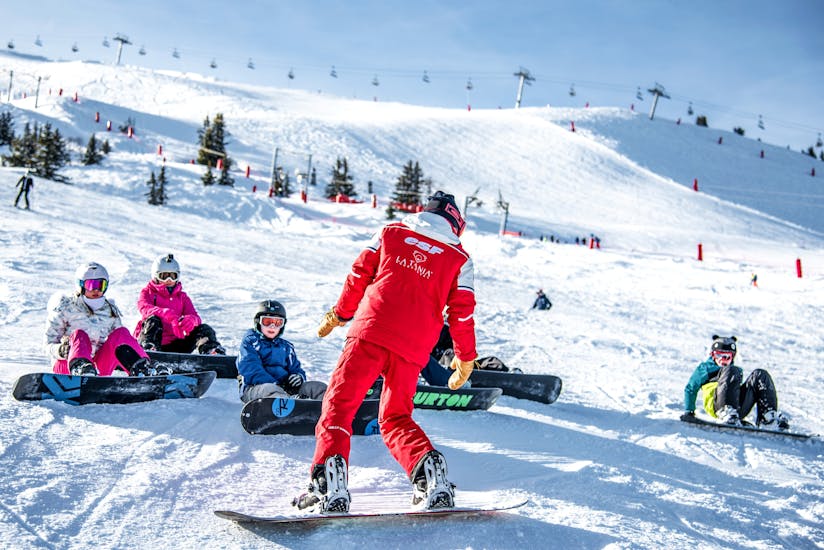 Kinderen luisteren naar hun leraar tijdens de snowboardles (vanaf 8 jaar) voor beginners.