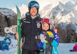 Een kind gaat op de foto met de snowboardleraar na geslaagde privélessen snowboarden voor kinderen en volwassenen (vanaf 4 jaar) van alle niveaus bij Skischule Grächen - Zenklusen Sport.