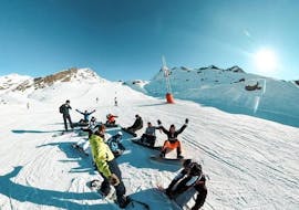 Des snowboardeurs sont assis dans la neige avant leur Cours de snowboard Adultes avec Prosneige Val Thorens & Les Menuires.