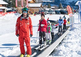 A group at the adult ski lessons + ski hire & transfer from Interlaken stands on the magic carpet, ready for their first descent with the Swiss Ski School Grindelwald.