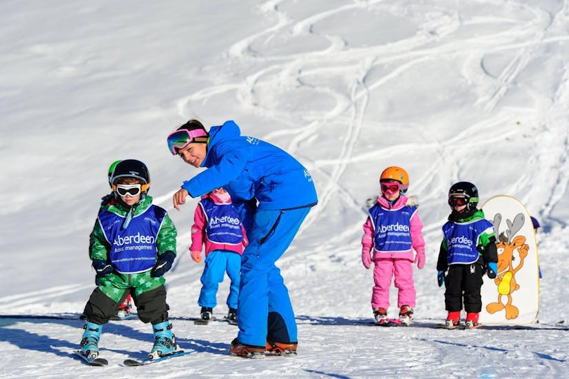 A ski instructor shows a child the correct technique at the kids ski lessons "Polar Bears" (3-5 yrs) for all levels with the Altitude Ski School Zermatt.