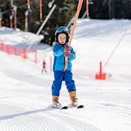 Un bambino prende uno ski lift baby durante le Lezioni di sci per bambini (3-4 anni) per principianti - Ski Start con Scuola di Sci Val di Sole.