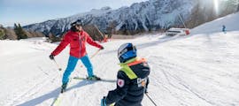 An instructor from Scuola di Sci Val di Sole is followed by a kid during the Kids Ski Lessons (5-14 y.) for All Levels - Junior Fun with Scuola di Sci Val di Sole.