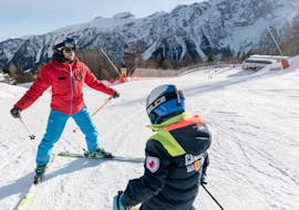 An instructor from Scuola di Sci Val di Sole is followed by a kid during the Kids Ski Lessons (5-14 y.) for All Levels - Junior Fun with Scuola di Sci Val di Sole.