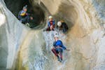 Menschen rutschen eine natürliche Rutsche hinunter während des Sportliches Canyoning in der Chli Schliere Schlucht mit Outdoor Switzerland AG.