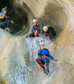 Mensen glijden van een natuurlijke glijbaan tijdens avontuurlijke canyoning in de Chli Schliere-kloof met Outdoor Switzerland AG.