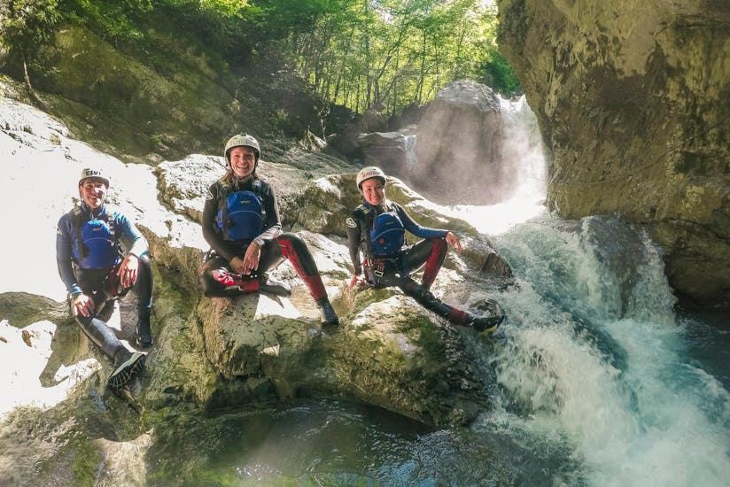 People sit on a rock in the middle of the gorge during Canyoning in the Saxeten Canyon for Beginners with Outdoor Switzerland AG.