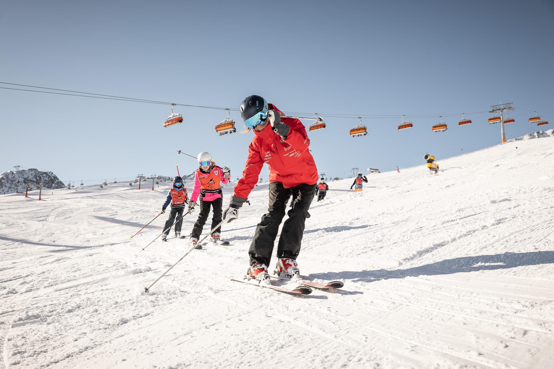 Children do an exercise after the ski instructor at the kids ski lesson (4-8 y.) for all levels incl. equipment hire with Ski School Vacancia Sölden.