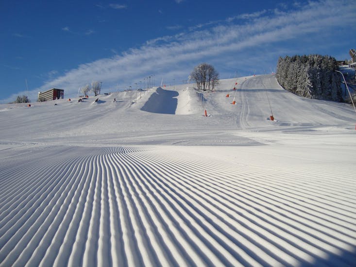The freshly prepared slopes await the first skiers at the kids ski lessons (8-12 y.) for beginners with start house - Fichtelberg Ski School.