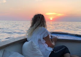 Una donna si gode il tramonto durante il giro privato in barca al tramonto lungo le Cinque Terre con Aquamarina Cinque Terre.