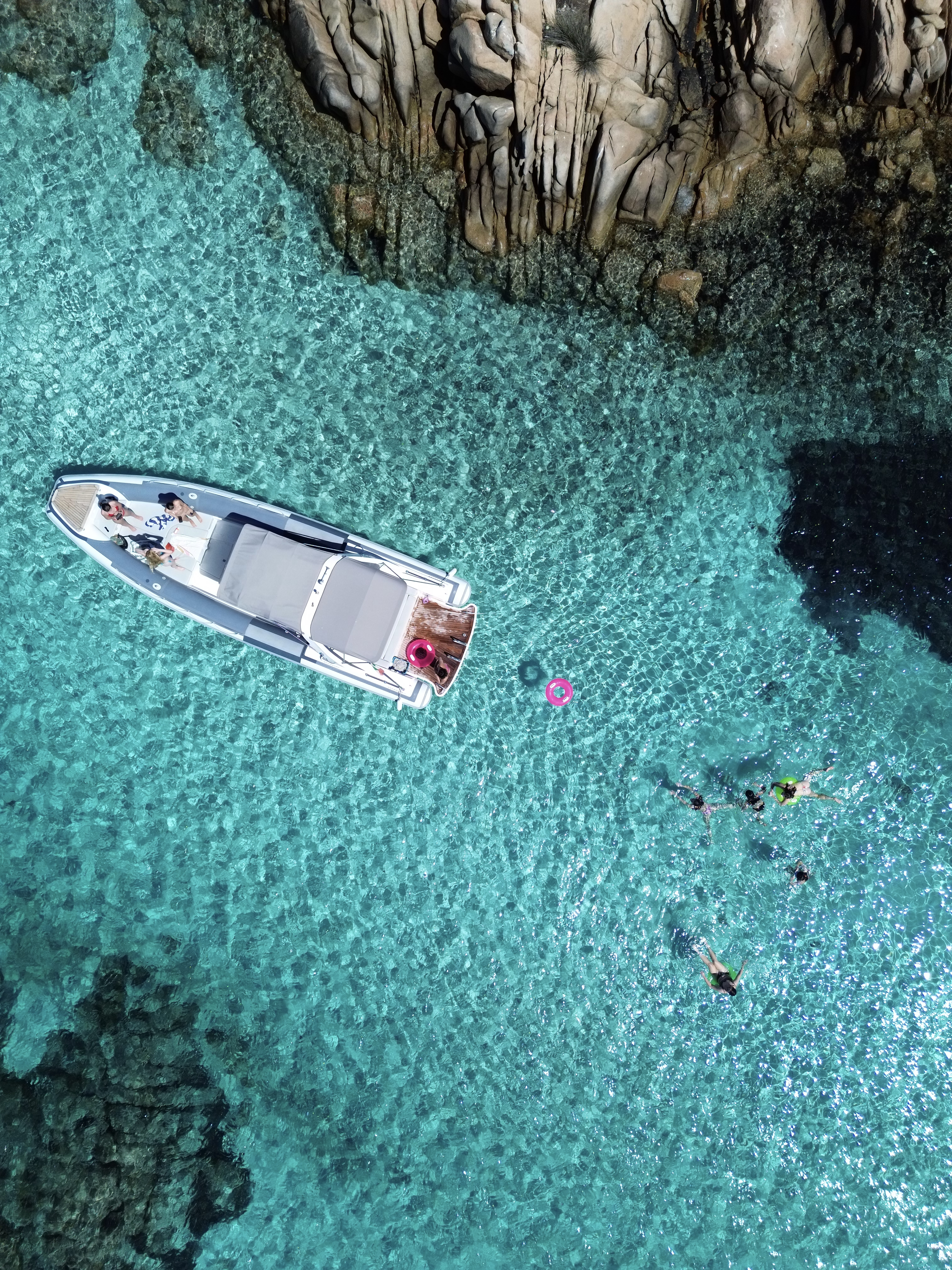 Vista aérea de los huéspedes relajándose en un barco y nadando en aguas cristalinas de color turquesa durante una excursión privada en el archipiélago de La Maddalena con Maxi Rib Excursions La Maddalena.