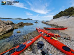 Four kayaks on a stone beach during a break of the Sea Kayak Tour from Zlarin to Prvić and Tijat - Half Day with Peak & Paddle Šibenik.