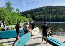 Teilnehmer am Blaibacher See, die sich auf Ihre SUP Tour vorbereiten für den SUP Verleih in Viechtach und am Blaibacher See mit Schneider Events.