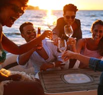 Foto van een groep deelnemers die een toost uitbrengen tijdens de RIB boottocht bij zonsondergang langs Lo Stagnone van Marsala met aperitief met Navigare le Egadi Favignana.