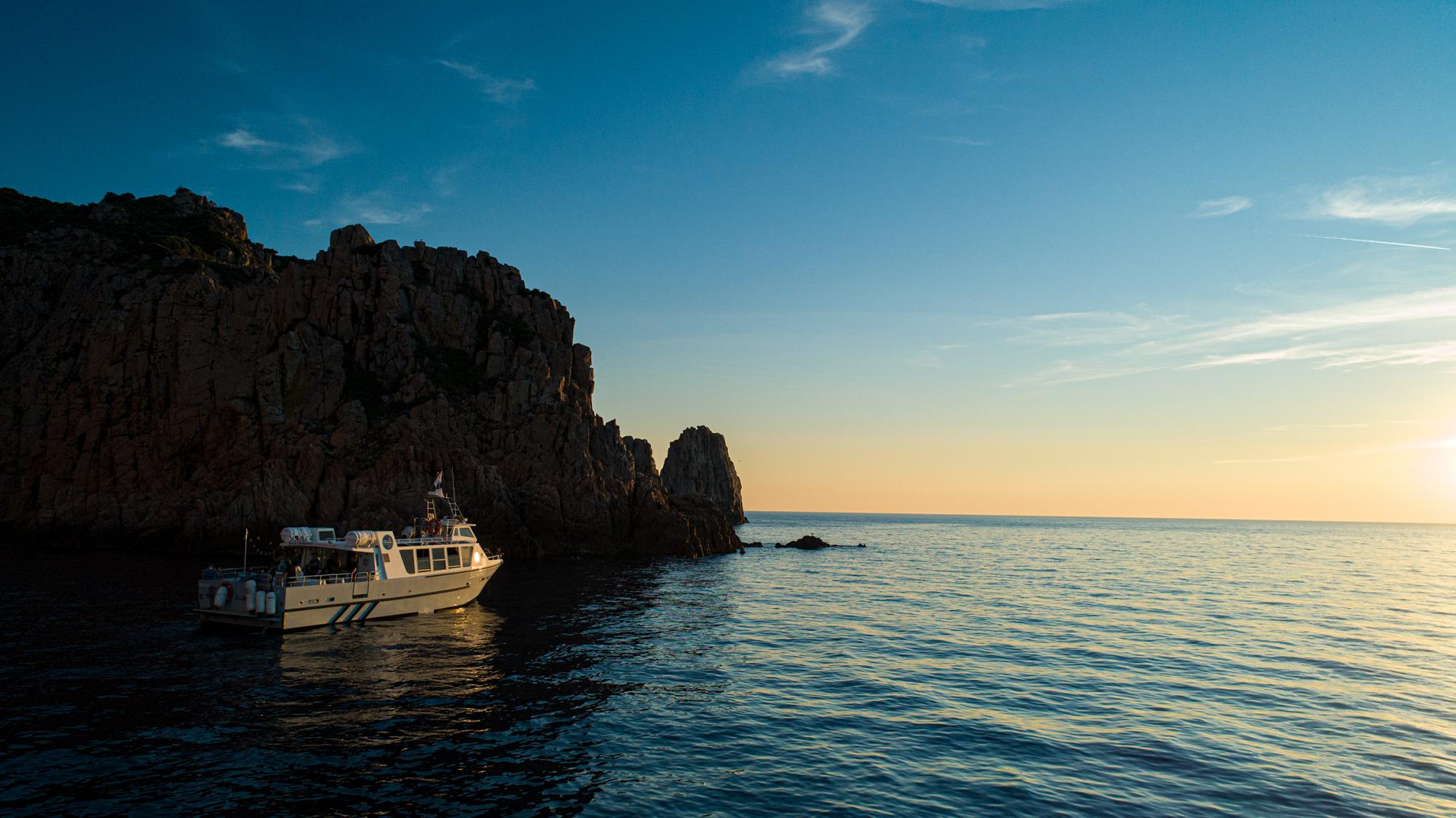 Bateau d'Isula Croisières naviguant jusqu'aux Calanques de Piana au coucher de soleil.