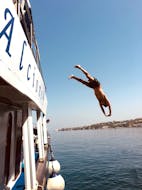 Eine Person springt während der Bootstour um Ischia mit Schwimmstopps und Mittagessen mit Alcione Boat Ischia vom Boot.