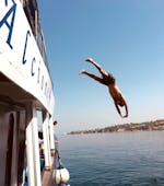 Una persona si tuffa dalla barca durante la Gita in barca intorno ad Ischia con soste per nuotare e pranzo con Alcione Boat Ischia.