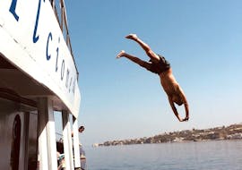 Una persona si tuffa dalla barca durante la Gita in barca intorno ad Ischia con soste per nuotare e pranzo con Alcione Boat Ischia.