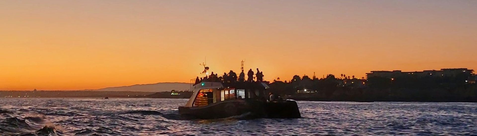 Das Boot während dem Sonnenuntergang über dem Meer bei der Katamarantour bei Sonnenuntergang zur Benagil-Höhle.