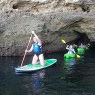 Persone che remano nella grotta durante il Giro in catamarano al tramonto alla Grotta di Benagil con kayak o SUP con SeaAlgarve Albufeira.