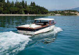 Un bateau en bois de style vénitien naviguant sur le lac de Garde utilisé pour une Balade privée en bateau à l'Isola del Garda avec Consolini Boats Garda.