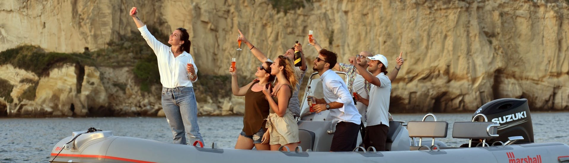 Les gens sur le bateau s'amusent pendant la Balade en bateau semi-rigide au coucher du soleil depuis Naples le long de la côte avec Apéritif avec Seaside Napoli organisée par Seaside Napoli.