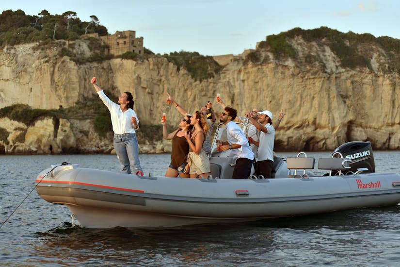 Leute auf dem Boot, die sich während der von Seaside Napoli organisierten privaten RIB Bootstour bei Sonnenuntergang von Neapel entlang der Küste mit Apéritif amüsieren.