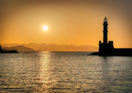 Foto di un tramonto sulle acque di Creta e del faro durante la gita in barca da Chania a Theodorou con spettacolo di sirene con Mermaid Tours.