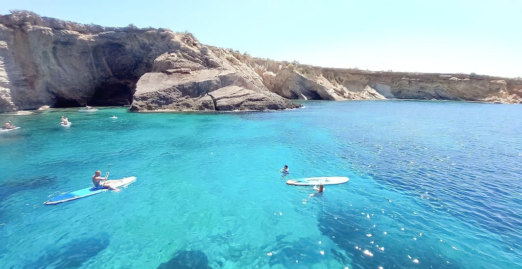 Turquoise waters on the coast of Ibiza and some people enjoying water activities in a private boat of Salvador Ibiza.
