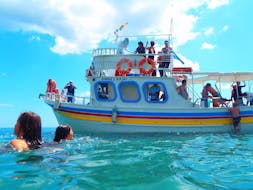 Everyone is around the boat, enjoying their swimming stop during the Boat Trip along the Coastline to Saint George's Bay with Zorbas Cruises Hersonissos.