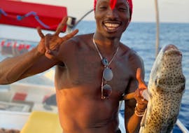 Un joven se alegra con su premio durante la excursión en barco de pesca al atardecer desde Hersonissos con Zorbas Cruises Hersonissos.