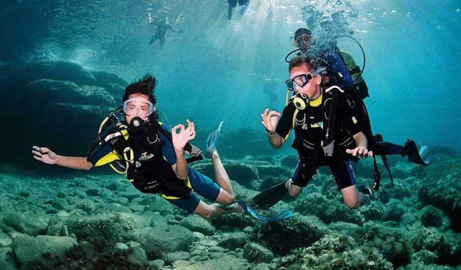 Zwei Personen machen Zeichensprache unter Wasser beim PADI Discover Scuba Diving in Sant Antoni de Portmany auf Ibiza für Anfänger von Arenal Diving & Boat Trips.