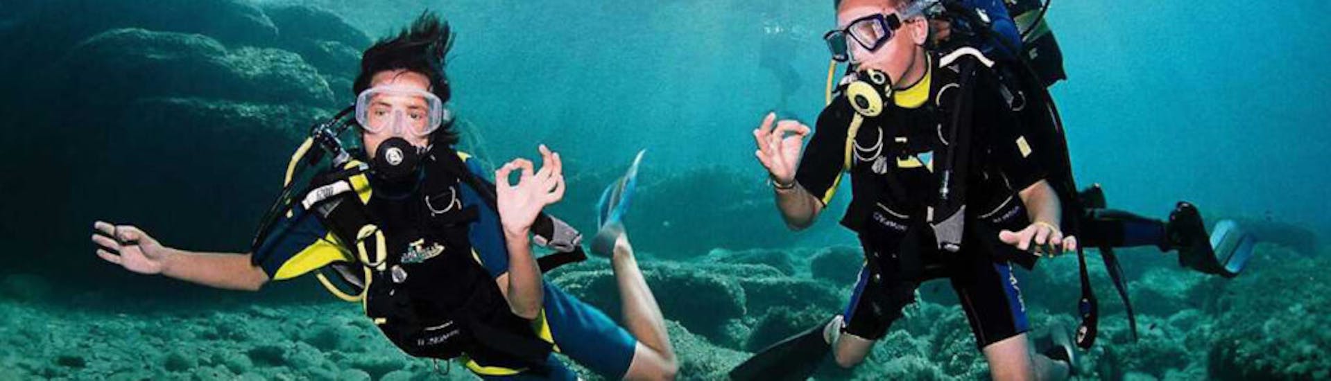Deux personnes faisant du langage des signes sous l'eau pendant la plongée sous-marine lors du Baptême de plongée à Sant Antoni de Portmany à Ibiza pour Débutants avec Arenal Diving & Boat tours.