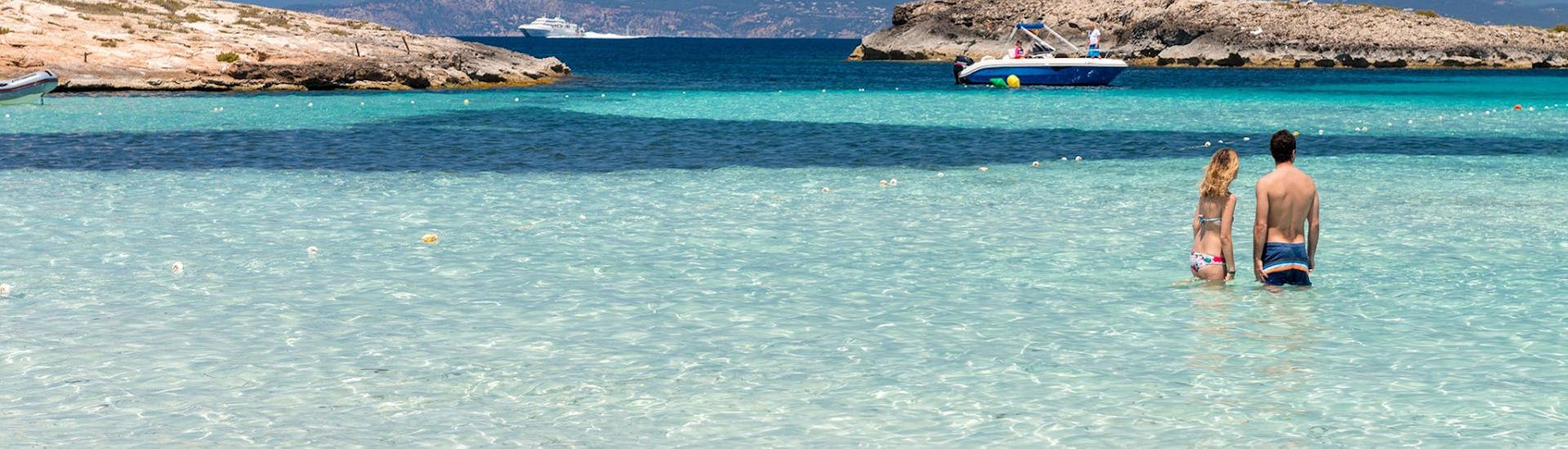La gente está en el agua en la hermosa playa que verás durante el paseo en catamarán a Cala Saona o Llevant con Apéritif con Sea Experience Ibiza.