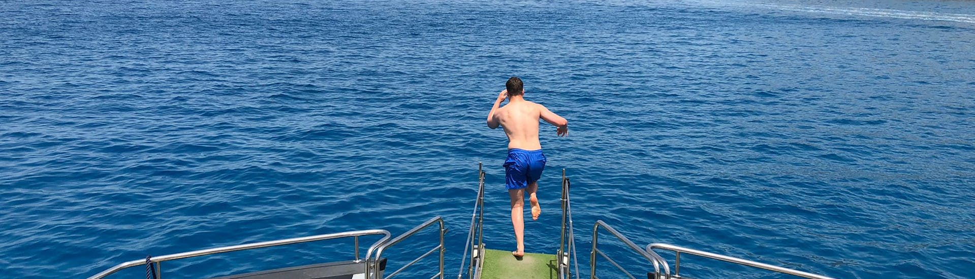 Ein Mann springt ins Wasser während der Katamaran-Tour rund um Ibiza mit Wassersport und Paella.