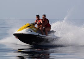 Ein Paar fährt mit voller Geschwindigkeit auf dem Jetski während des Jet Ski in Malia mit Dolphin Water Sports.