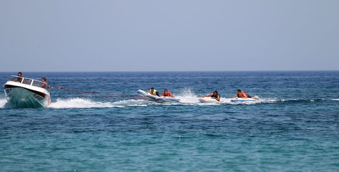The people on the sliders are struggling during the Banana Boat activity and other inflatables at Malia beach with Dolphin Water Sports.