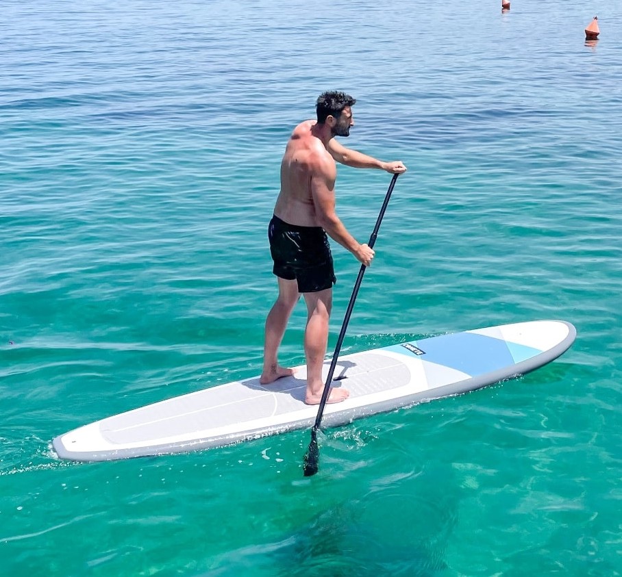 Un hombre rema durante el alquiler de SUP en la playa de Malia en Creta con Dolphin Water Sports.