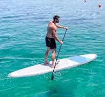 Un uomo pagaia durante il noleggio SUP sulla spiaggia di Malia a Creta con Dolphin Water Sports Malia.
