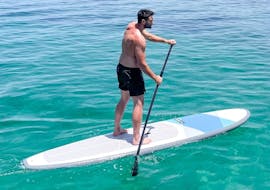Un hombre rema durante el alquiler de SUP en la playa de Malia en Creta con Dolphin Water Sports.