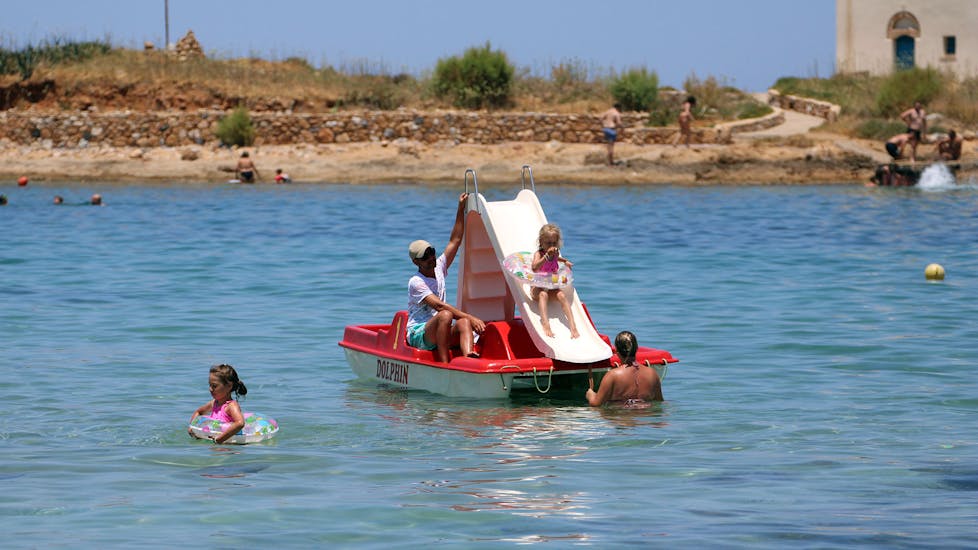 A family is having fun around the pedal boat during the Pedal Boat at Malia beach in Crete with Dolphin Water Sports.