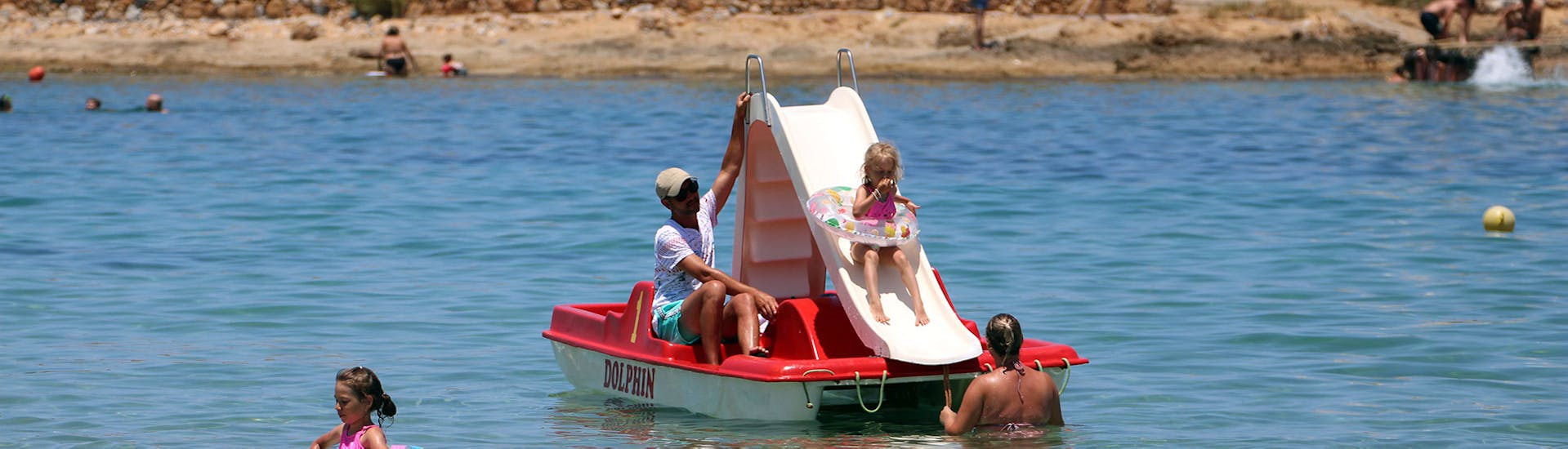 Eine Familie vergnügt sich auf dem Tretboot während des Tretbootrennens am Strand von Malia auf Kreta mit Dolphin Water Sports.