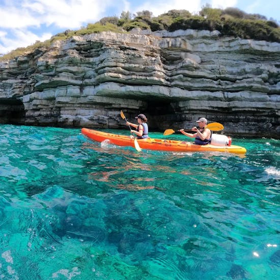 Kayak de mer dans les eaux bleues de la mer Adriatique devant une grotte pendant l'excursion en kayak de mer dans les grottes de Pula par Pula Adventure Team.
